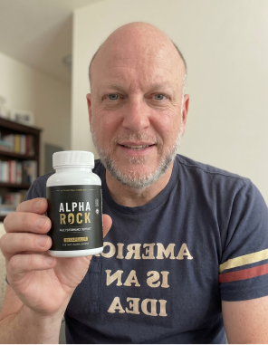 An adult man holding a bottle of AlphaRock capsules, shown as an illustrative editorial visual